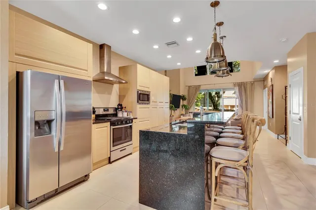 a kitchen with stainless steel appliances kitchen island granite countertop a refrigerator and a sink