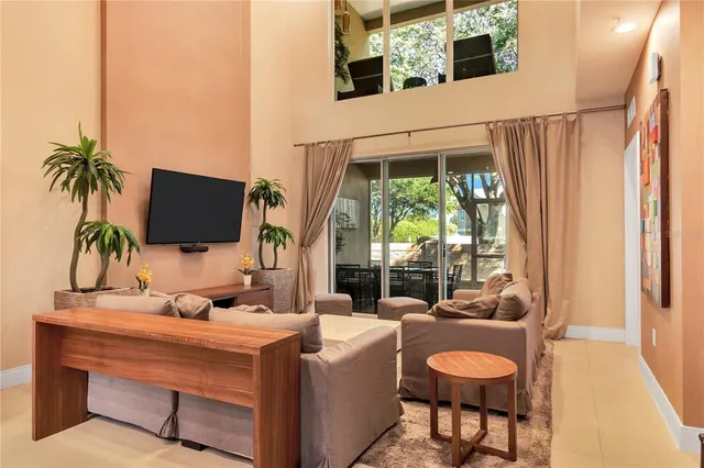 a living room with furniture a flat screen tv and a floor to ceiling window