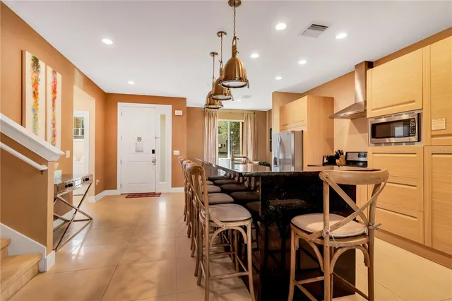 a dining room with stainless steel appliances kitchen island granite countertop a table chairs and a refrigerator
