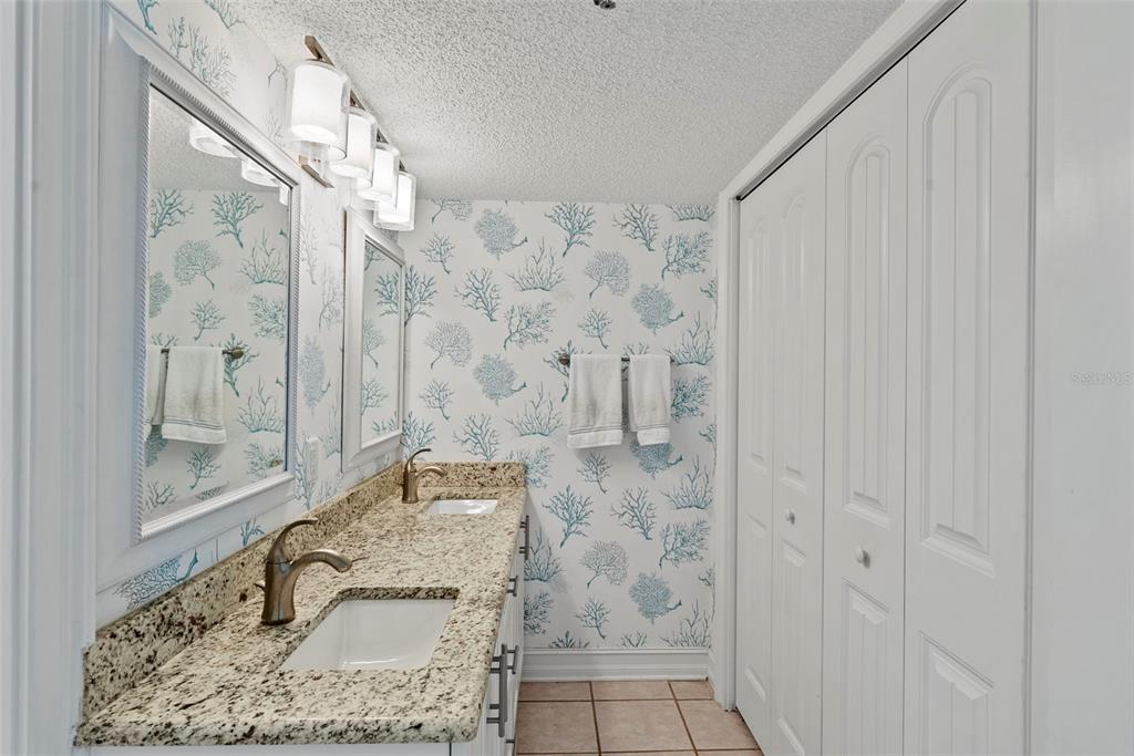 13650 Gulf Boulevard, Unit 604 Madeira Beach, FL 33708 - Photo 36 of 71 a bathroom with a granite countertop sink a mirror and shower