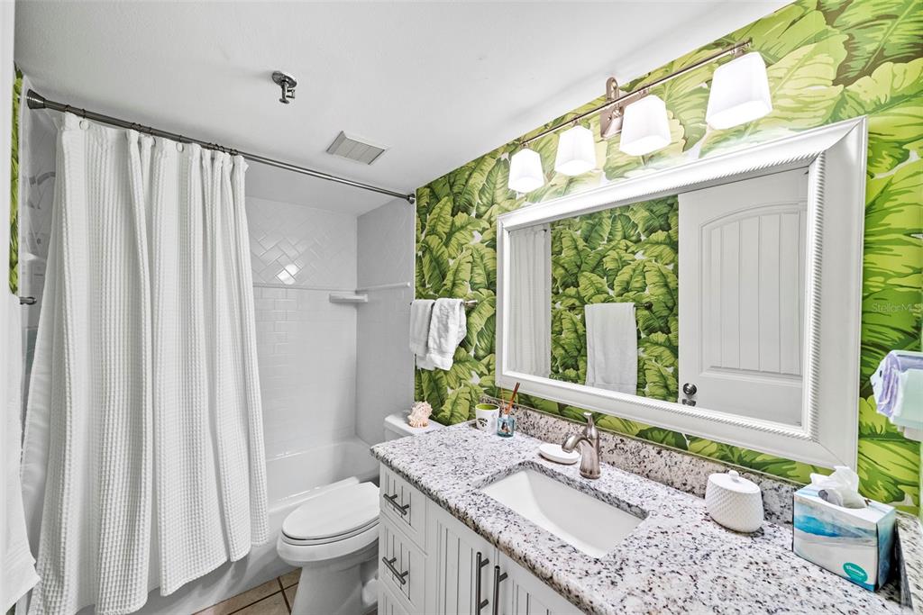13650 Gulf Boulevard, Unit 604 Madeira Beach, FL 33708 - Photo 42 of 71 a bathroom with a granite countertop sink a toilet and a mirror