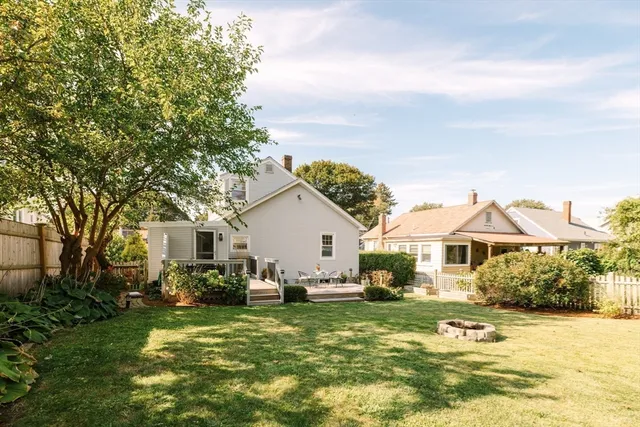 a view of a white house next to a yard with a fountain and large trees
