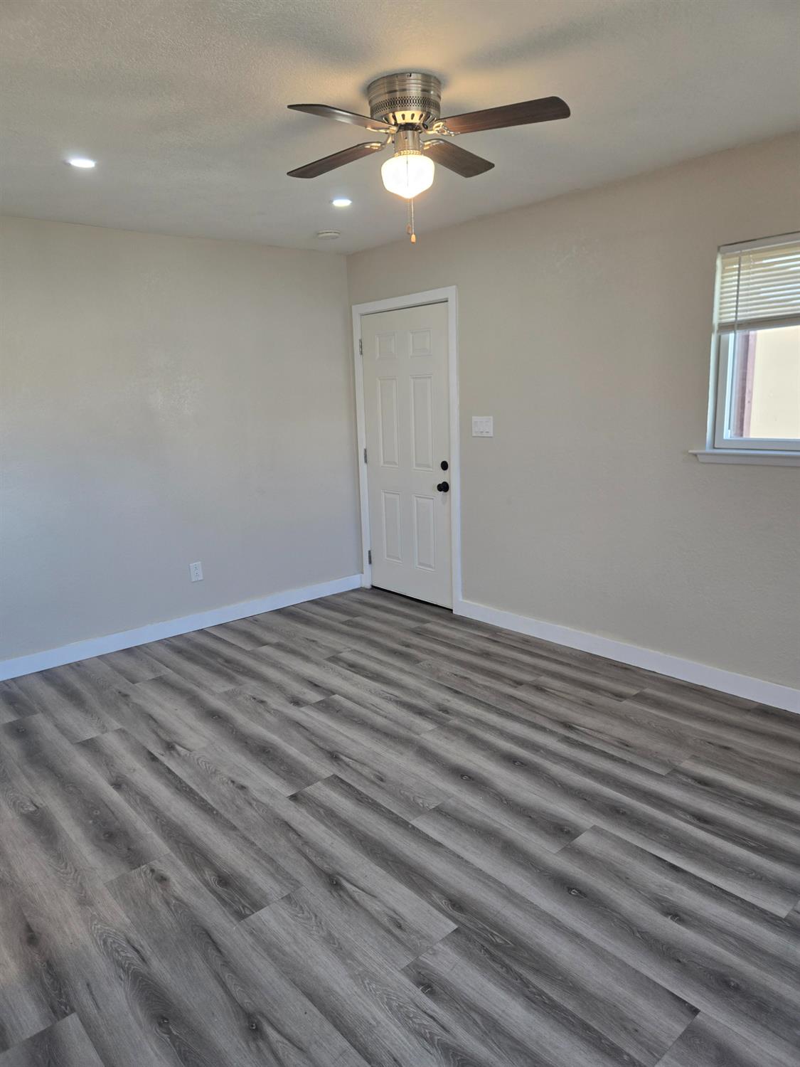 a view of a room with wooden floor and a ceiling fan