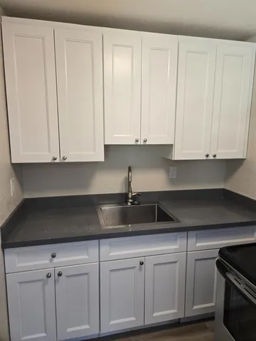 a kitchen with white cabinets and sink