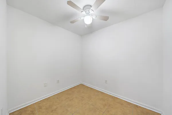 an empty room with a chandelier fan and ceiling fan