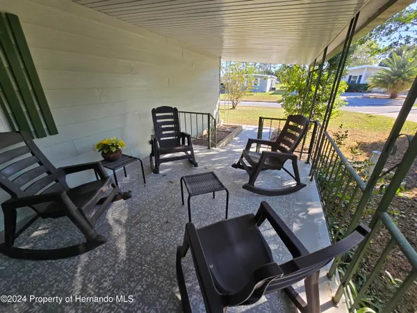 a view of a porch with chairs and floor to ceiling window