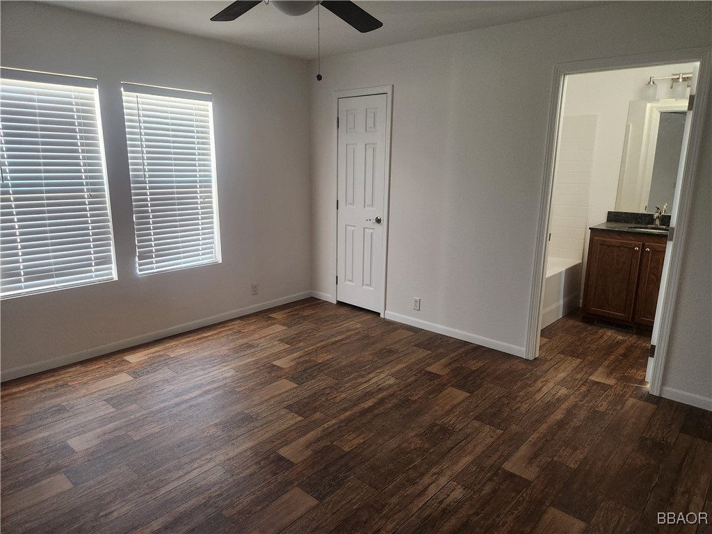 60784 Stagemans Road Landers, CA 92285 - Photo 7 of 9 an empty room with wooden floor a ceiling fan and windows