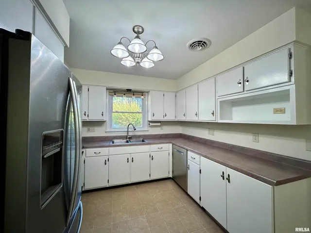 a kitchen with a sink stainless steel appliances cabinets and a window