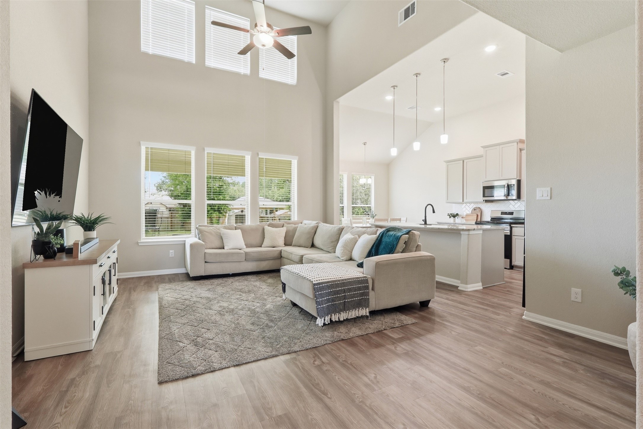 6310 Fawn Path Drive Conroe, TX 77303 - Photo 12 of 41 Spacious open-concept living area featuring soaring ceilings, luxury vinyl plank flooring, abundant natural light, and seamless flow into the kitchen—perfect for everyday living and entertaining.