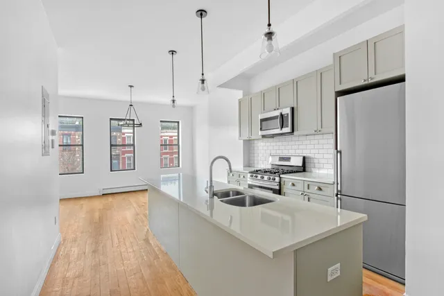 a kitchen with stainless steel appliances granite countertop a sink dishwasher a stove and white cabinets with wooden floor