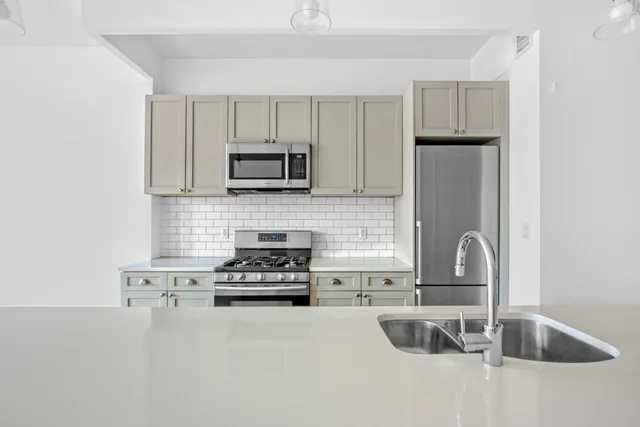 a kitchen with stainless steel appliances granite countertop a sink a stove a refrigerator a center island with wooden floor and cabinets