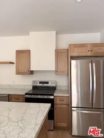 a kitchen with granite countertop a refrigerator and a stove top oven