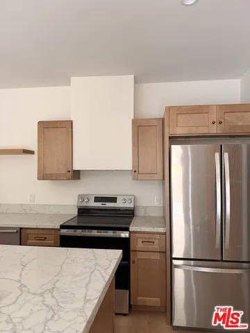 a kitchen with granite countertop a refrigerator and a stove top oven