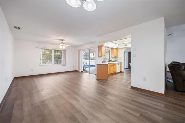 a view of empty room with kitchen and wooden floor