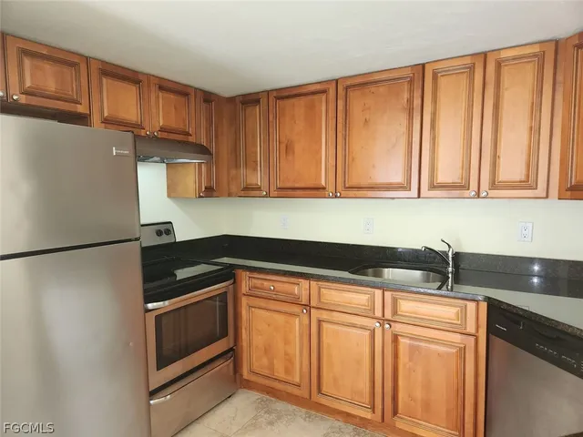 a kitchen with granite countertop white cabinets and refrigerator