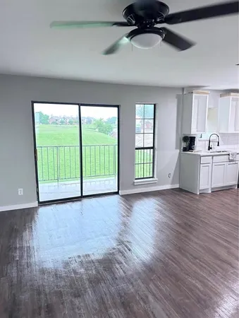 a view of an empty room with a window and wooden floor
