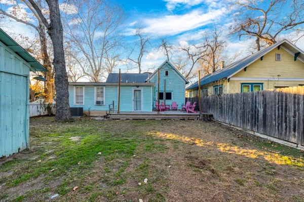a backyard of a house with wooden fence and large trees