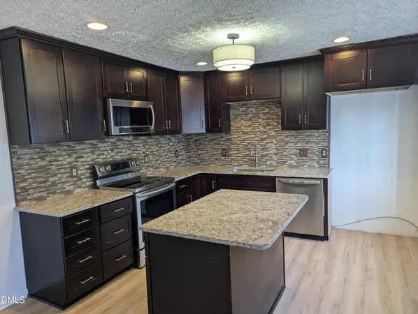a kitchen with stainless steel appliances kitchen island granite countertop wooden cabinets and granite counter tops