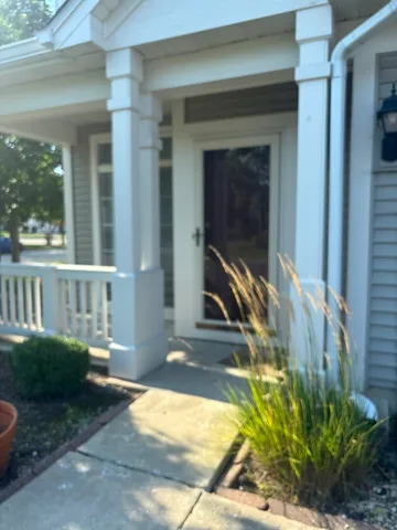 a view of a house with a small yard and floor to ceiling window and potted plants