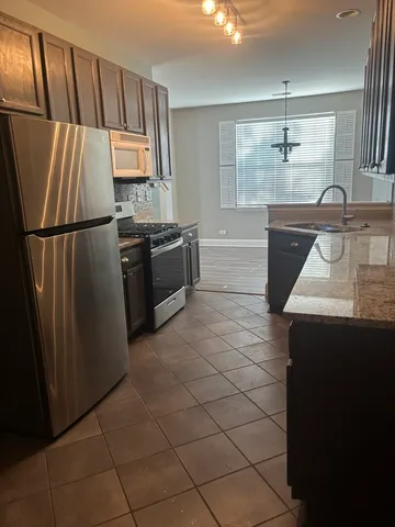 a kitchen with granite countertop a refrigerator and a sink