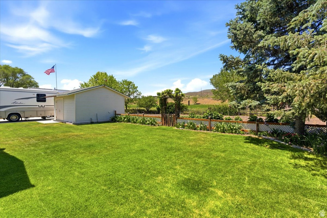 72 Canal Bank Road Garland, UT 84312 - Photo 29 of 40 Expansive lawn area featuring a white storage shed and mature evergreen trees