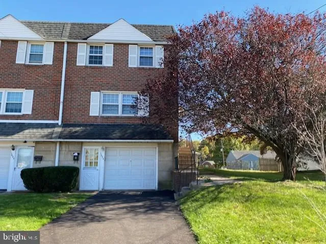 a front view of a house with a yard and a tree