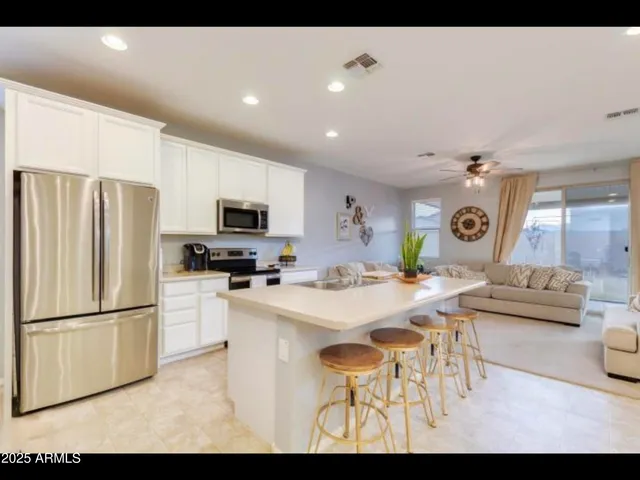 a kitchen with stainless steel appliances kitchen island granite countertop a refrigerator a stove a microwave oven a dining table and chairs with wooden floor