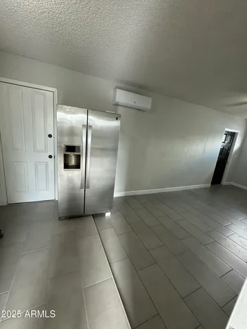 a view of a refrigerator in kitchen and an empty room