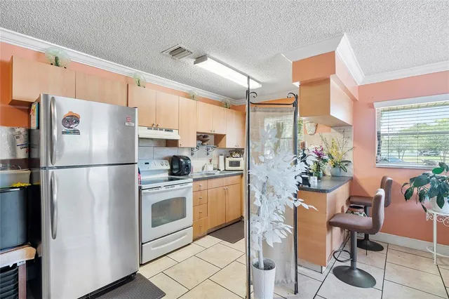 a kitchen with stainless steel appliances a refrigerator sink and chairs