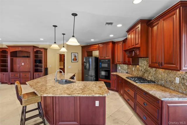 a kitchen with granite countertop a stove a sink a refrigerator and wooden cabinets
