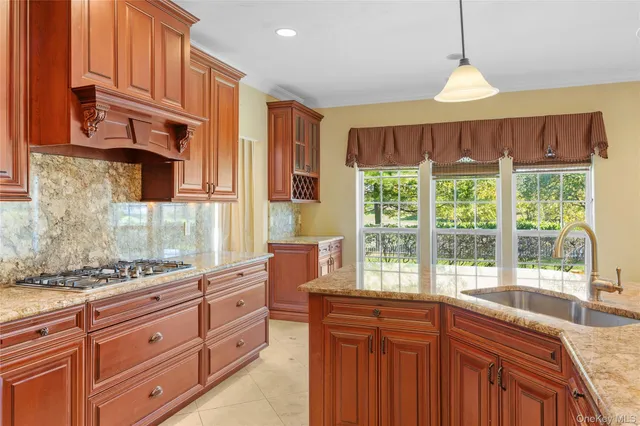 a kitchen with stainless steel appliances granite countertop a stove a sink dishwasher and wooden cabinets with large windows