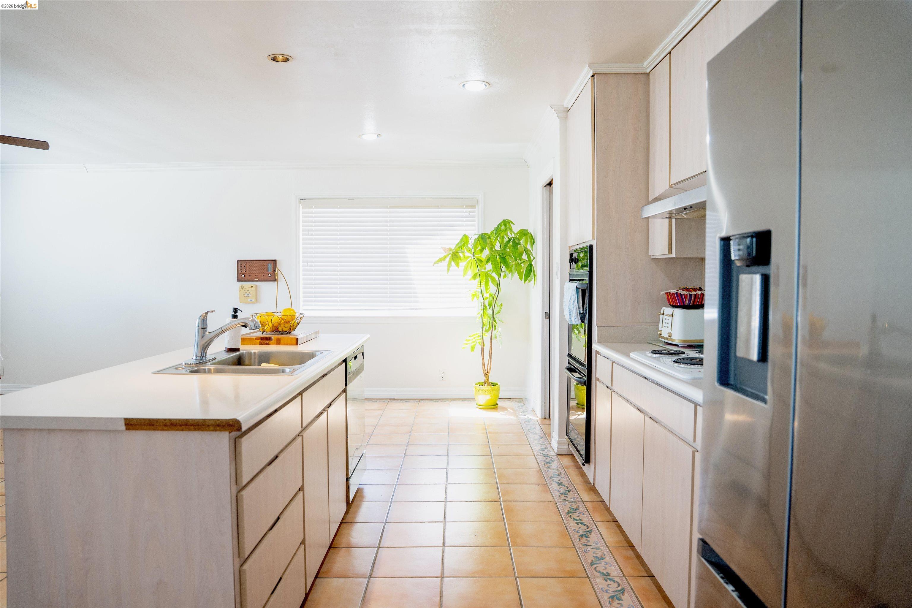 64 Washington Street Novato, CA 94947 - Photo 6 of 21 Kitchen featuring a central island with an integrated sink, light-toned cabinetry, stainless steel appliances including a refrigerator and double wall ovens, and terracotta-style floor tiling