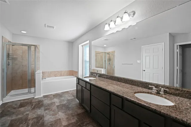 a spacious bathroom with a granite countertop double vanity sink a bathtub and shower