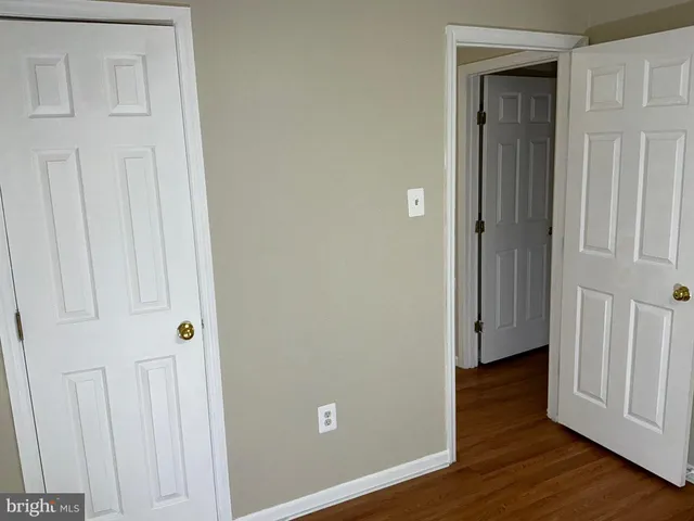 an empty room with wooden floor and closet area