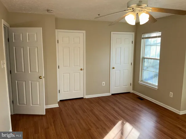 an empty room with wooden floor cabinet and windows