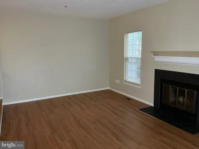 a view of empty room with wooden floor and fireplace