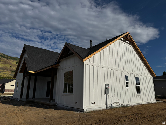 389 West 2100 South Perry, UT 84302 - Photo 5 of 21 Board and batten siding, dark-toned roof, exposed wood rafter tails, multiple windows, covered entry