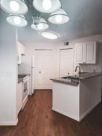 a kitchen with granite countertop white cabinets and wooden floor