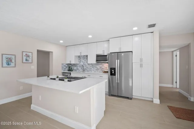 a kitchen with kitchen island stainless steel appliances a refrigerator stove top oven and sink