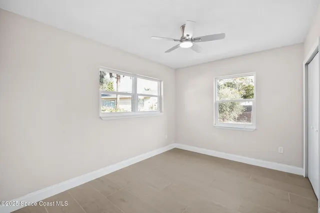 an empty room with windows and fan