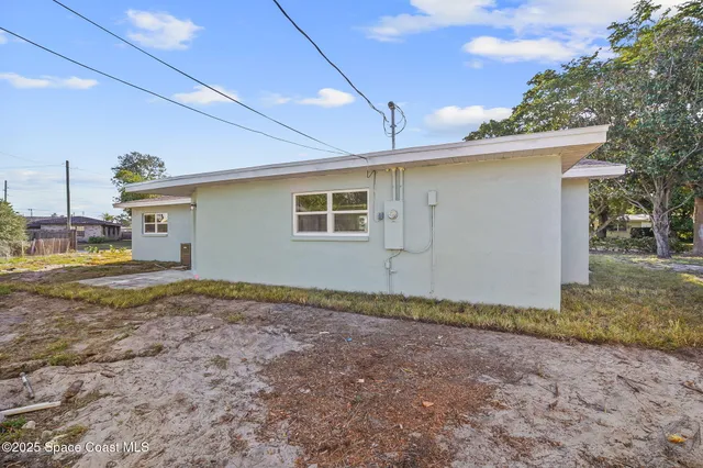 a view of a house with backyard and trees in the background