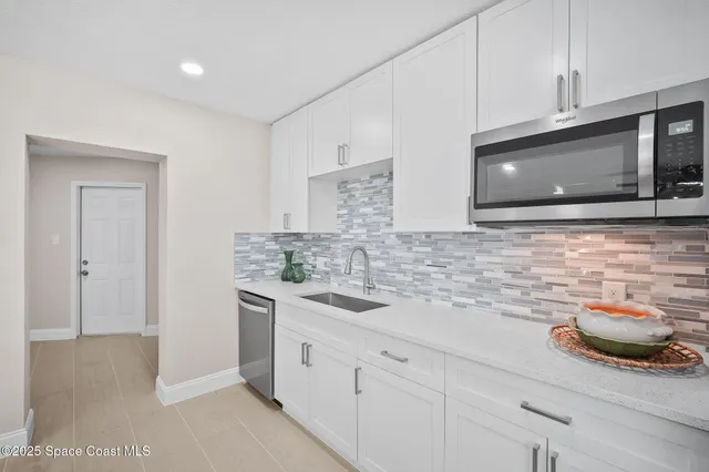 a kitchen with stainless steel appliances a sink dishwasher stove and microwave with wooden floor