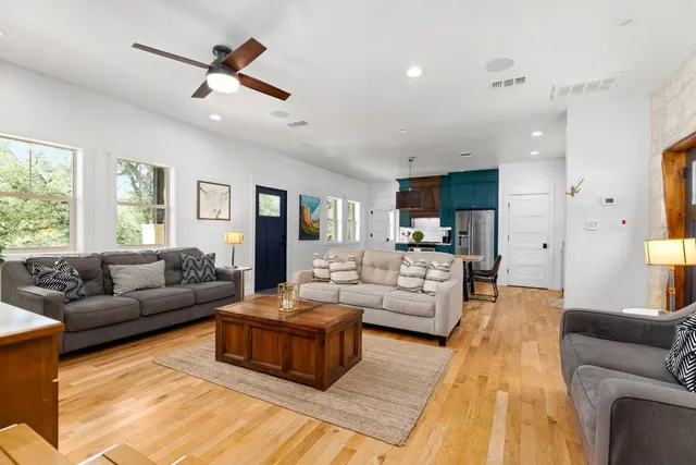 a kitchen with stainless steel appliances kitchen island granite countertop a sink dishwasher a stove and a refrigerator with wooden floor