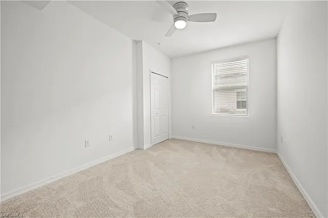 an empty room with a window and ceiling fan