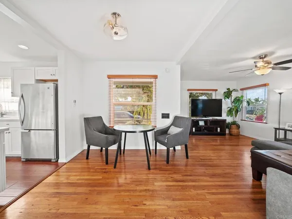 a living room with furniture a dining table and a refrigerator with wooden floor