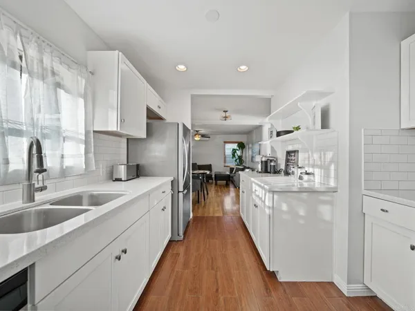 a kitchen with counter top space a sink wooden floor and stainless steel appliances