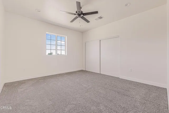 an empty room with a window and a ceiling fan