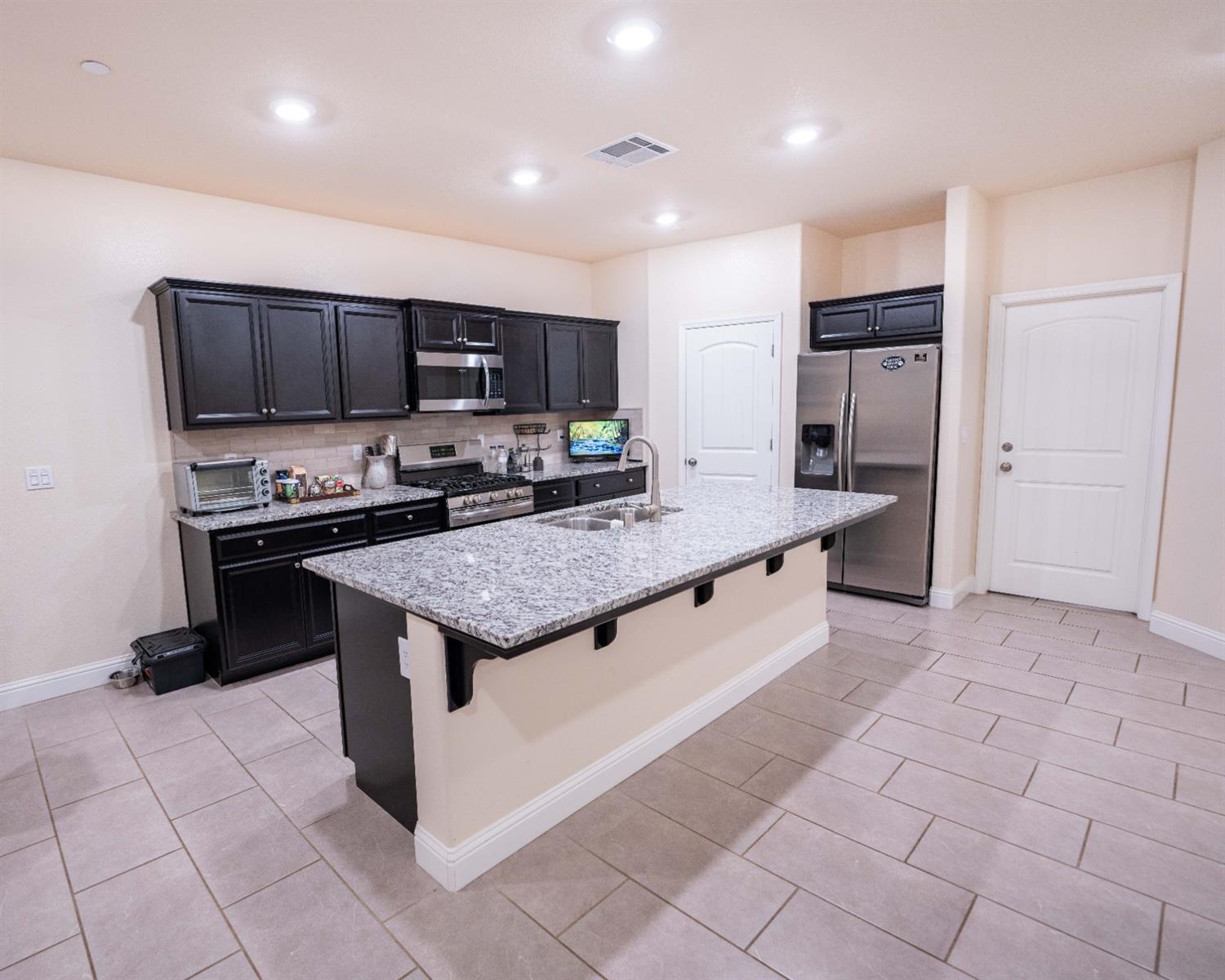 1818 Softwind Drive Tulare, CA 93274 - Photo 17 of 46 a kitchen with stainless steel appliances granite countertop a stove a sink and a refrigerator