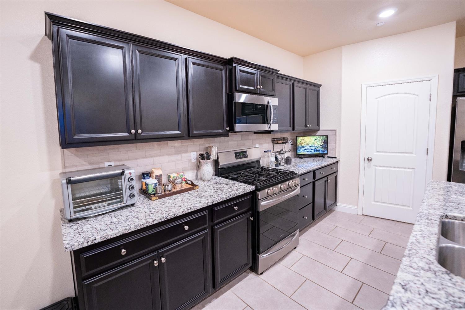 1818 Softwind Drive Tulare, CA 93274 - Photo 22 of 46 a kitchen with stainless steel appliances granite countertop a stove a sink and a microwave