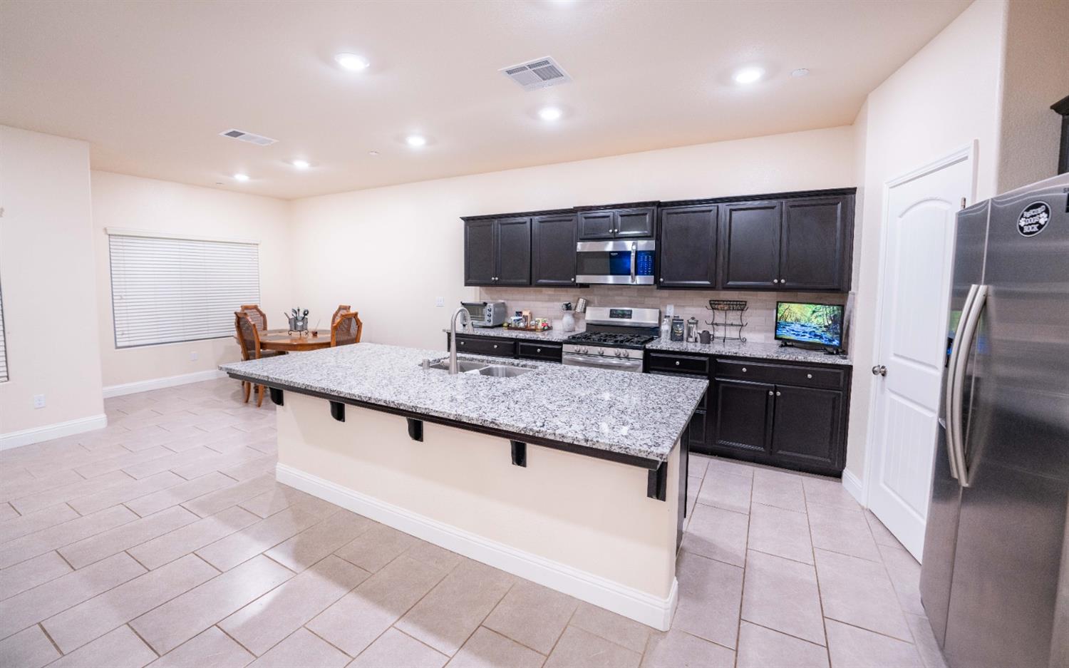 1818 Softwind Drive Tulare, CA 93274 - Photo 23 of 46 a kitchen with stainless steel appliances kitchen island granite countertop a refrigerator a stove a sink a counter top and oven